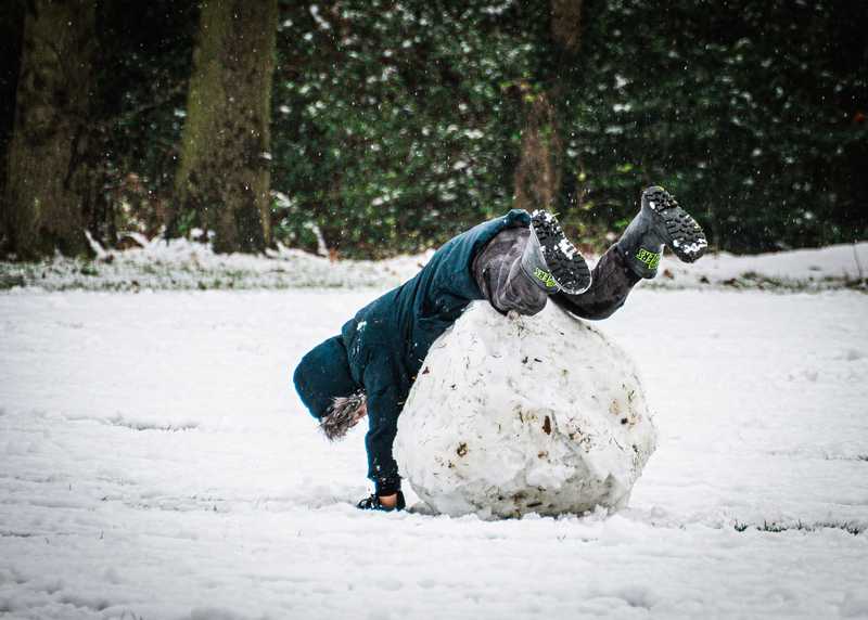 "Boy with huge snowball falling over it"