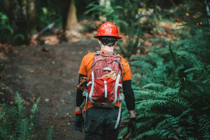"A man in a hard hat and harness on a trail"